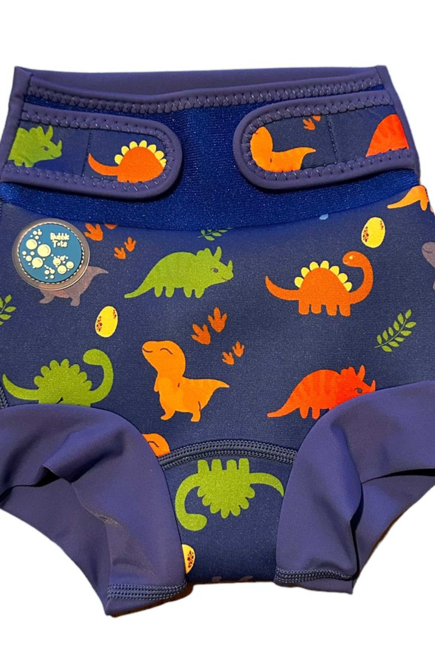 Bubble Tots Go Anywhere Swim Nappy Blue Dinosaurs Design An image of the Bubble Tots Go Anywhere Swim Nappy in Blue Dinosaurs design. The design features playful Dinosaurs, Eggs and Prints.